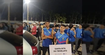Dois jovens atletas de vôlei de areia com uniformes azuis, segurando uma placa com o nome Santa Rita do Trivelato, ao lado de outras pessoas em um evento esportivo. Crédito: Instagram Santa Rita Do Trivelato.