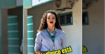 Mulher sorrindo em frente ao CRAS Nenice Pereira Leite, com crachá da Prefeitura de Mirassol d'Oeste - MT, explicando sobre o Cadastro Único