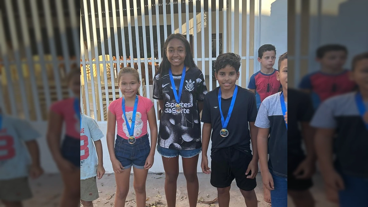 Crianças pulando em sacos em uma corrida divertida, com uma mulher observando. Créditos: Cultura Marcelândia / Instagram.