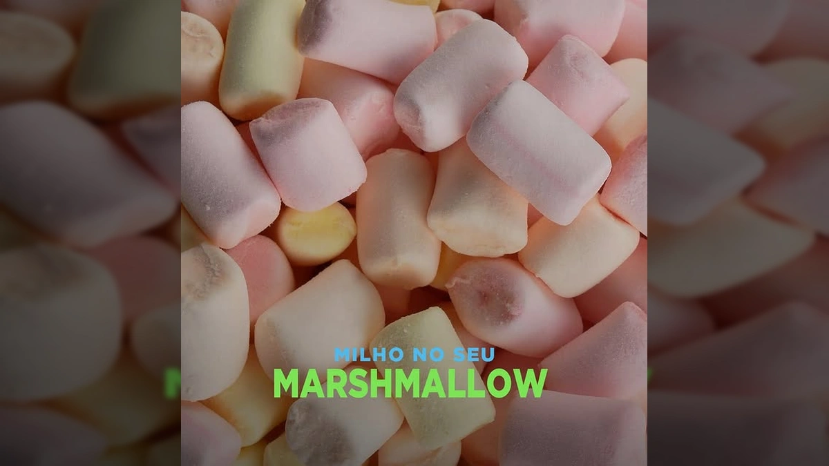 Imagem de uma mulher sorrindo em um campo de milho, com um chapéu, óculos de sol, segurando um marshmallow e uma embalagem. Créditos: Aprosoja Mato Grosso / Instagram.