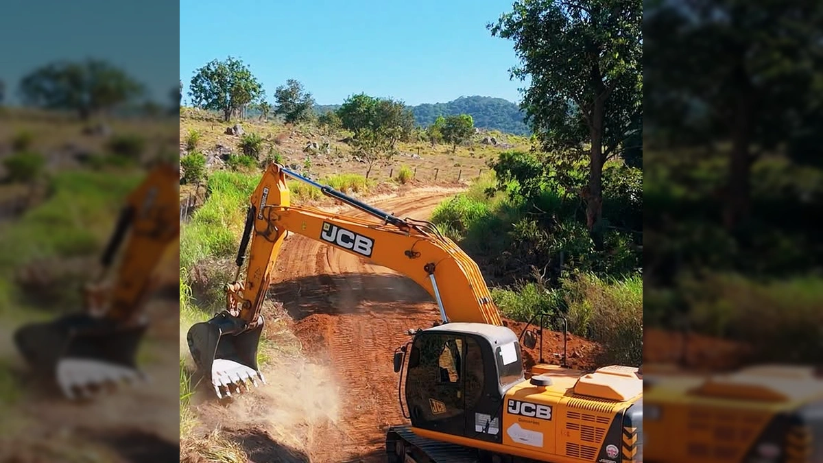 Máquina escavadeira JCB trabalhando em estrada de terra vermelha, com pilhas de terra e pedras ao lado. Crédito: Governo de Vila Rica-MT / Instagram