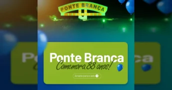 Placa de 'Ponte Branca' iluminada à noite, com balões azuis flutuando e logo da AMM. Crédito: AMM (Associação Mato-grossense dos Municípios).