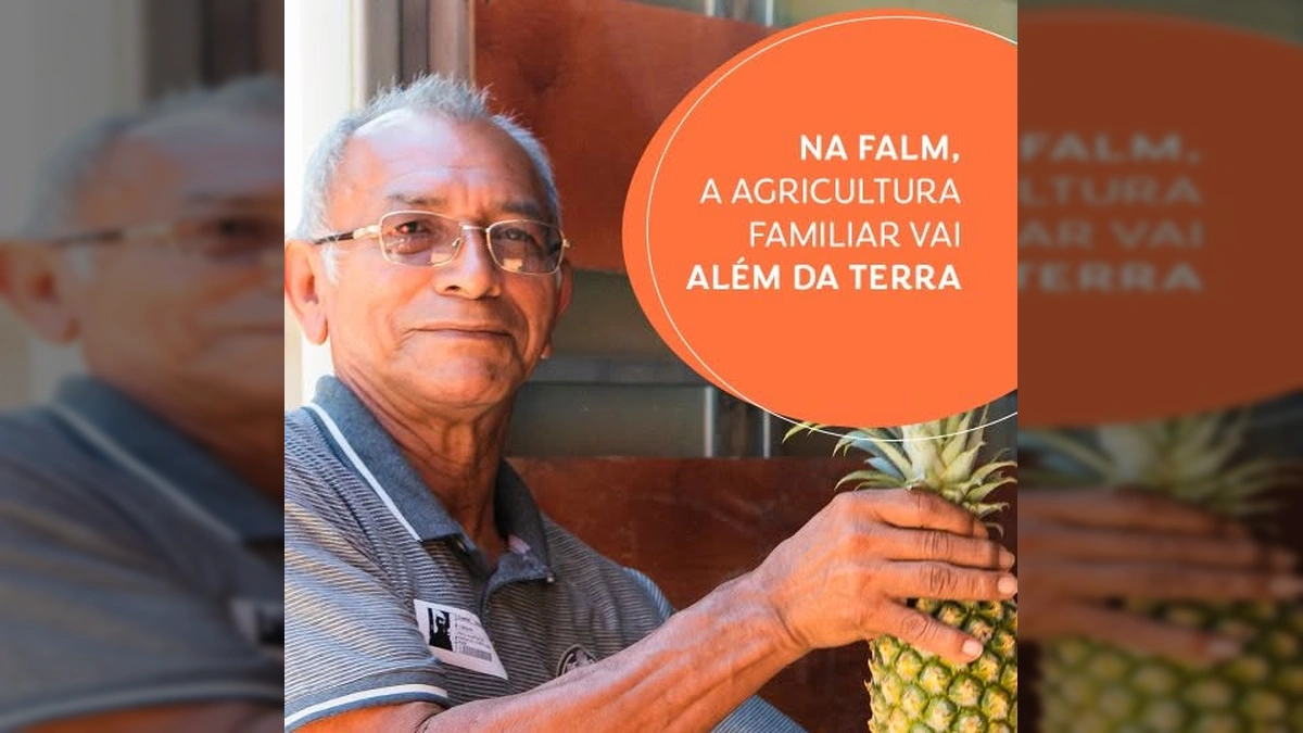 Homem sorrindo segurando um abacaxi, com logo da FALM e Amaggi ao fundo. Crédito: sigafalm