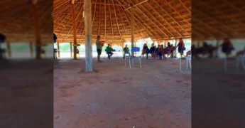 Grupo de pessoas reunidas sob um telhado de palha, ouvindo apresentação sobre o programa FUNDAAF. Créditos: Prefeitura de Querência-MT / Instagram.