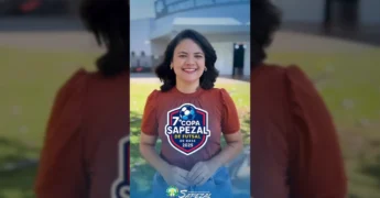 Mulher sorridente em frente a um ginásio, falando sobre a Copa Sapezal de Futsal de Base / Crédito: Prefeitura de Sapezal