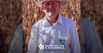 Ademir Fischer, um produtor rural em Lucas do Rio Verde, Mato Grosso, sentado em uma cadeira, com seu chapéu e camisa branca, em meio a árvores, representando a vida no campo e o sucesso no agronegócio. Crédito: Aprosoja Mato Grosso / Instagram