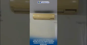Imagem da Casa de Apoio de Cotriguaçu, no Mato Grosso, mostrando um dos ar-condicionados doados pela Câmara Municipal, com cortinas brancas e um ventilador ao lado. Créditos: Prefeitura Municipal de Cotriguaçu / Instagram.