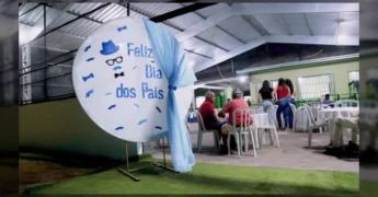 Foto da festa de Dia dos Pais em Vila Rica, Mato Grosso, mostrando a decoração e mesas postas, com pessoas interagindo e a secretária Clelma Lopes ao microfone. Créditos: governodevilaricaoficial.