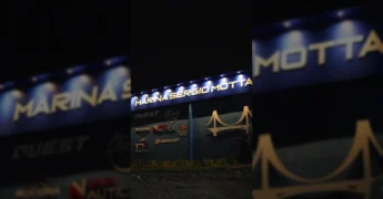 Entrada da Marina Sergio Motta com placas de marcas náuticas e pessoas celebrando a inauguração, crédito @nauticaxoficial no Instagram.