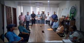 Grupo de homens e mulheres em uma sala de reunião, com homens em pé ao fundo e mulheres sentadas à mesa, durante anúncio de benefício. Créditos: Prefeitura de Juscimeira / Instagram.
