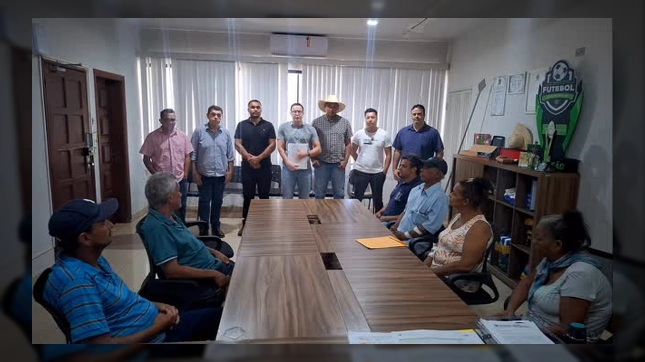 Grupo de homens e mulheres em uma sala de reunião, com homens em pé ao fundo e mulheres sentadas à mesa, durante anúncio de benefício. Créditos: Prefeitura de Juscimeira / Instagram.