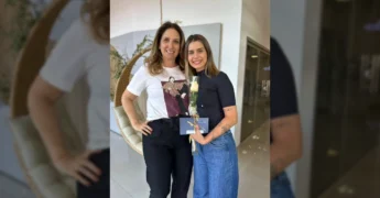 Foto de uma das finalistas do Miss Água Boa 2025 recebendo um convite e flores. Créditos: missaguaboa / Instagram