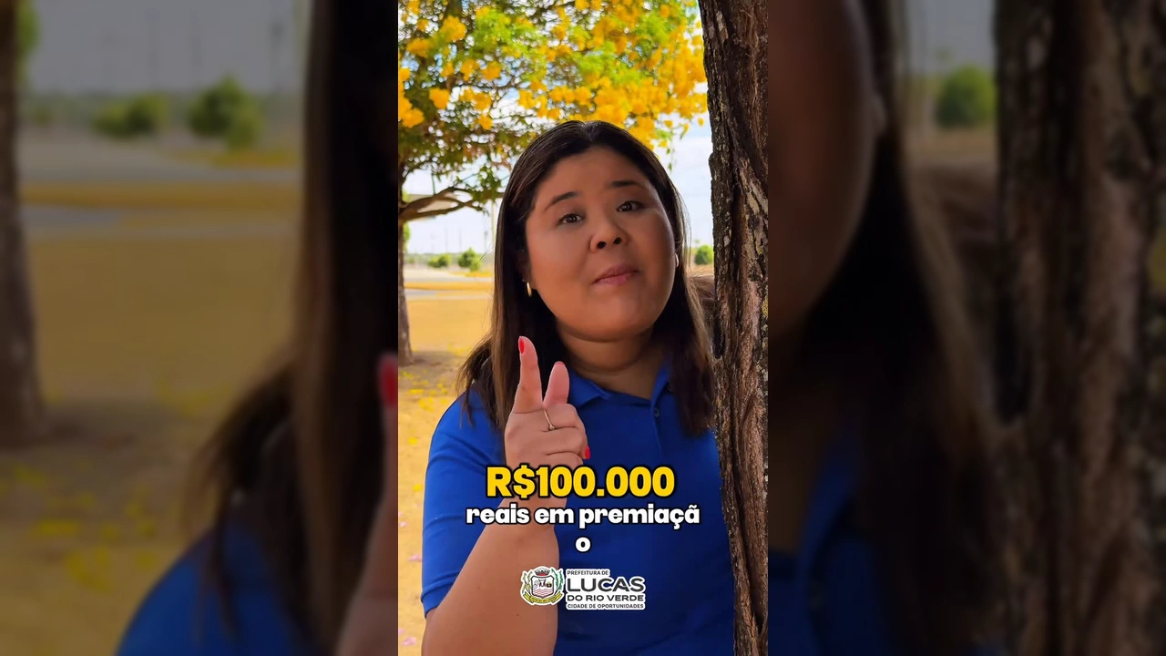 Mulher sorridente em polo azul divulgando evento de corrida em Lucas do Rio Verde, com árvore e parque ao fundo. Crédito: Prefeitura de Lucas do Rio Verde / Instagram