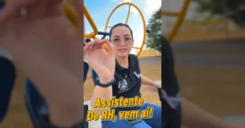 Mulher feliz em óculos, camiseta preta 'Guarantã do Norte', jeans, sentada em equipamento de academia ao ar livre, com celular na perna. Créditos: Prefeitura Municipal / Instagram.