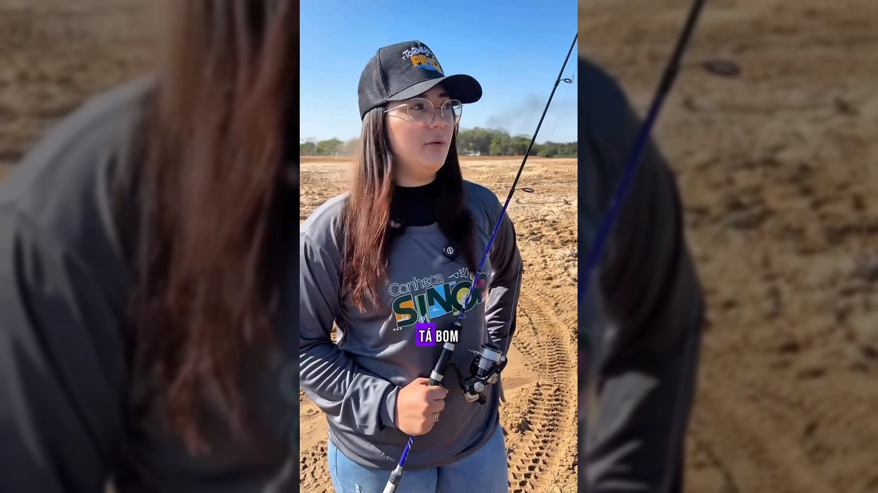 Foto de uma mulher com boné e óculos, com uma vara de pesca na mão, em uma paisagem de areia e um rio ao fundo, preparando-se para o Torneio de Pesca em Sinop. Crédito: Festeja Sinop / Instagram.
