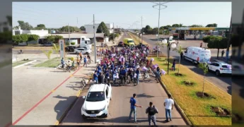 Grupo de ciclistas vestindo lilás e azul, muitos com balões roxos, pedalando em uma rua de Vera, MT. Crédito: Prefeitura Municipal de Vera / Instagram