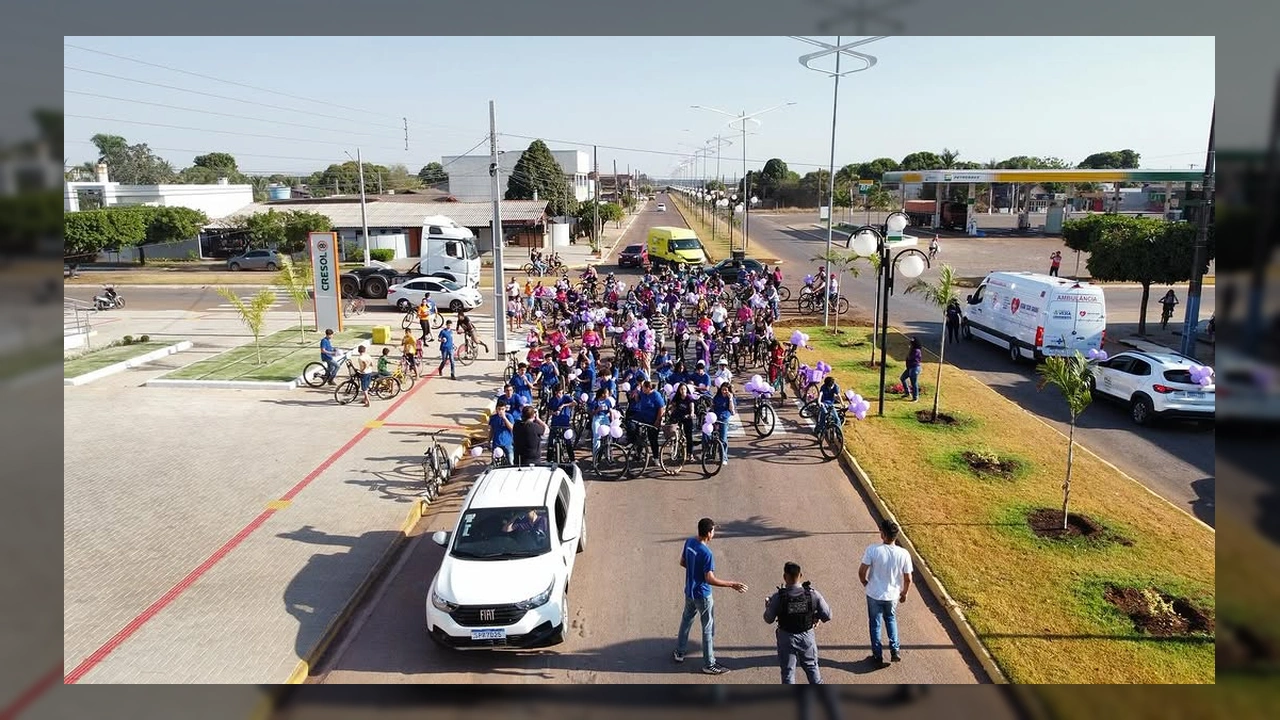 Grupo de ciclistas vestindo lilás e azul, muitos com balões roxos, pedalando em uma rua de Vera, MT. Crédito: Prefeitura Municipal de Vera / Instagram