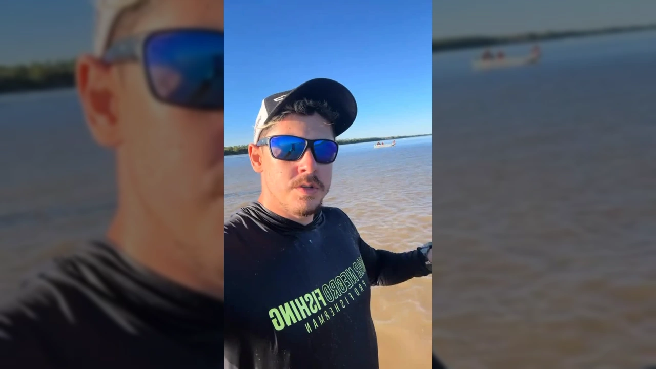 Homem em rio turvo cercado por peixes saltando, destacando a fartura de espécies no Araguaia. Créditos: Mauro Mendes / Instagram