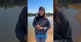 Mulher na margem do Rio Teles Pires com a imagem da santa, divulgando a Romaria Náutica. Crédito: Festeja Sinop / Instagram