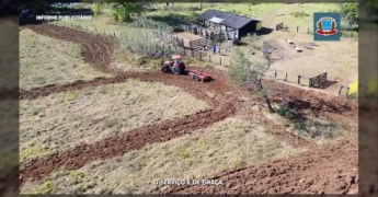 Trator vermelho arando o solo em uma área rural de Jaciara, Mato Grosso, com o implemento de gradagem visível. Crédito: Prefeitura de Jaciara / Instagram.