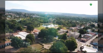Imagens aéreas de Rosário Oeste, Mato Grosso, mostrando a cidade, rios, lagos e áreas verdes, com destaque para a igreja e a antiga prefeitura.