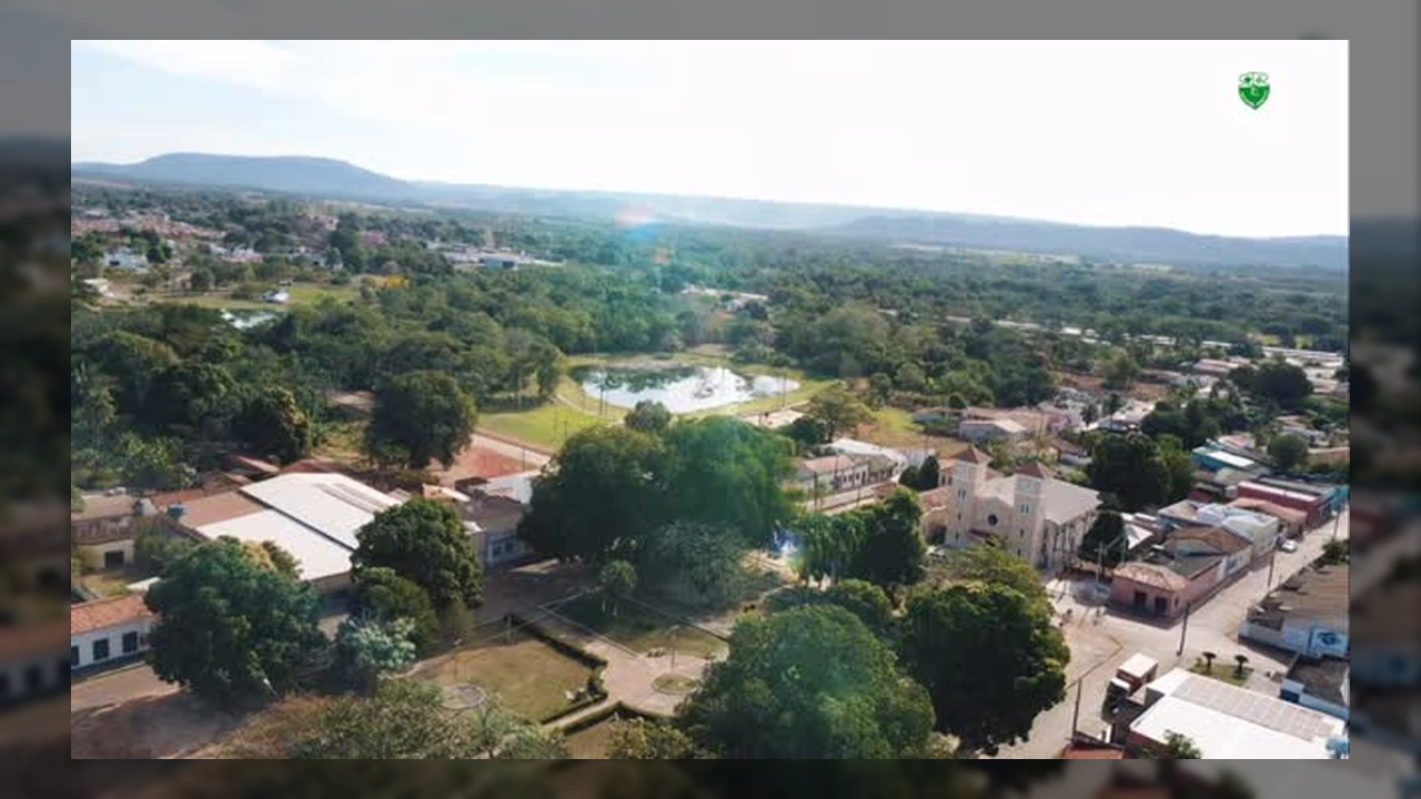 Imagens aéreas de Rosário Oeste, Mato Grosso, mostrando a cidade, rios, lagos e áreas verdes, com destaque para a igreja e a antiga prefeitura.
