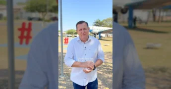 Homem de camisa listrada convidando para a Feira na Praça de Canarana, com avião ao fundo. Créditos: prefcanaranamt / Instagram