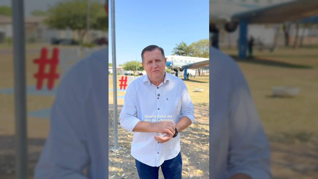 Homem de camisa listrada convidando para a Feira na Praça de Canarana, com avião ao fundo. Créditos: prefcanaranamt / Instagram
