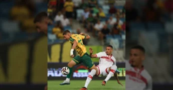 Imagem de um jogador do Cuiabá, camisa amarela e verde, em lance de ataque contra um jogador do CRB, camisa branca, durante partida da Série B. Crédito: AssCom Dourado / Instagram fmfmt_oficial