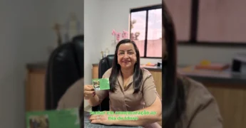 Imagem de uma mulher sorridente segurando um convite verde, em um escritório, convidando para o evento do Dia do Idoso em União do Sul, crédito: Prefeitura Municipal de União do Sul-MT / Instagram.