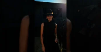 Mulher vestida de cowgirl com chapéu preto, vestido marrom, falando sobre a Expo Diamantino 2025. Créditos: expodiamantino / Instagram