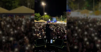 Nando Moreno se apresentando em palco para uma multidão com luzes de celulares acesas, no Porto do Baé, Barra do Garças. Créditos: Prefeitura de Barra do Garças / Instagram.
